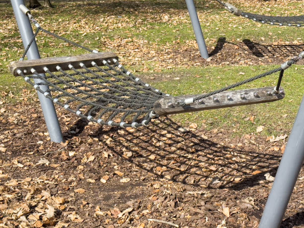 istock Park hammock amid fallen leaves in autumn with sunlit shadows 2205134417