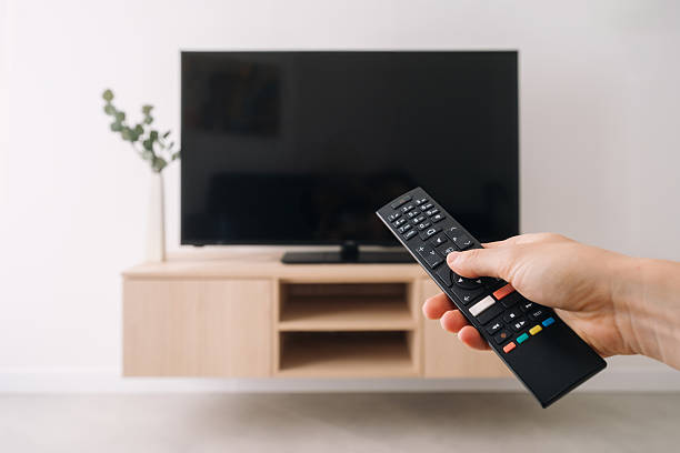 Modern living room with flat screen television and remote control in hand