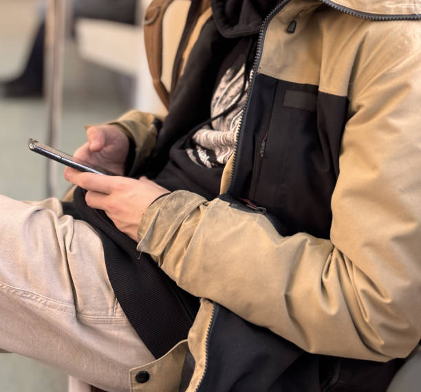 istock Casual Comfort A Young Man Engaged with His Smartphone in a Relaxed and Comfortable Setting. A young man is casually using his smartphone while comfortably sitting in a public space, fully relaxed 2205135271