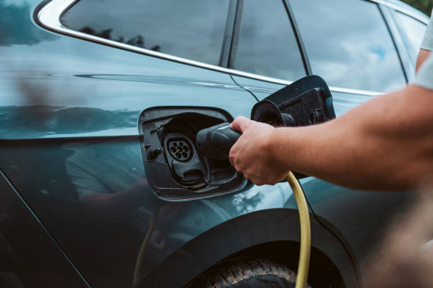 istock Man charging electric car, plugging charger in charging port. 2205136109