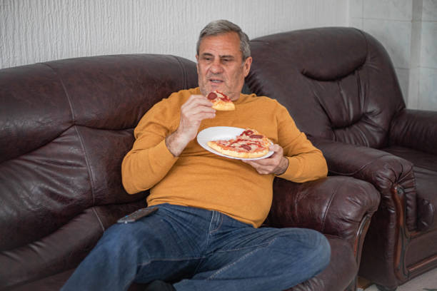 istock Overweight man watching TV and eating 2205136788