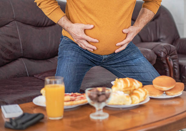 istock A man with a big belly eats food 2205136844