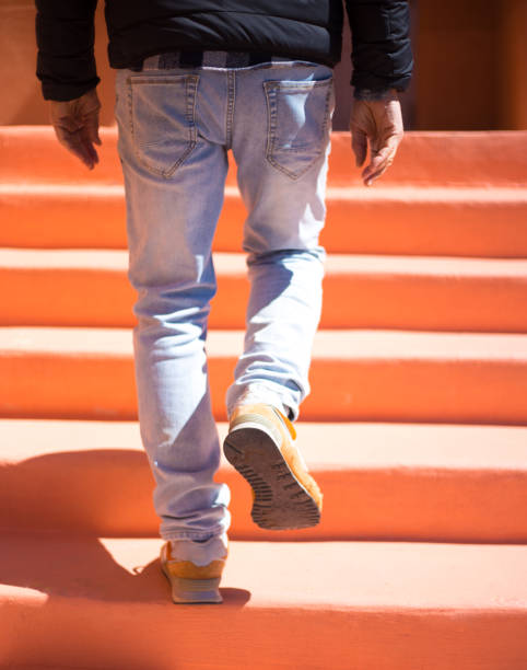 Man's Legs Going Up Orange Steps Close-Up, Copy Space