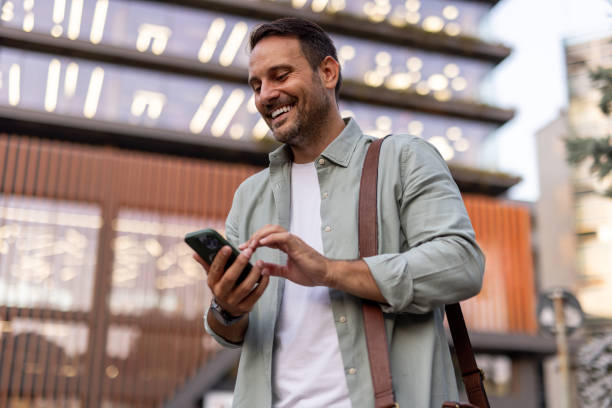 istock Smiling businessman using smartphone in front of modern office building 2205138560