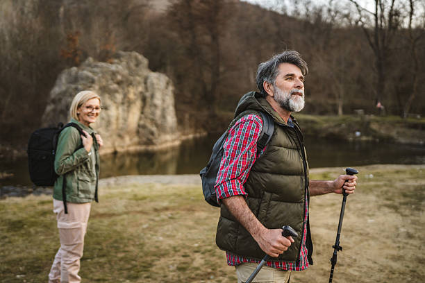 istock mature man hiker backpacker explore forest and river with hiking sticks 2205139571