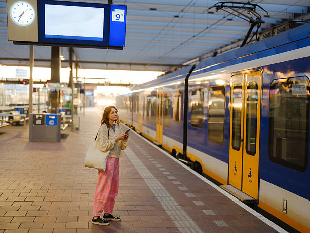 istock Woman using smartphone waiting for the train in Amsterdam 2205139770