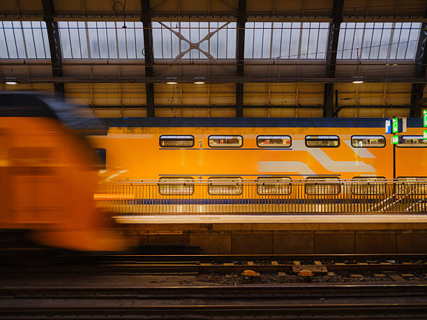 Yellow train on railway station in Amsterdam, Netherlands at dusk