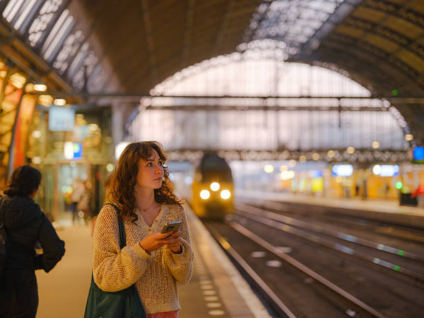 istock Woman using smartphone waiting for the train in Amsterdam 2205139823