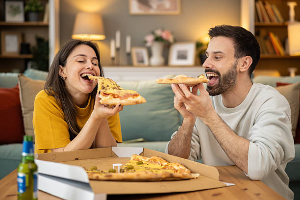 istock Couple sharing pizza slices joyfully 2205139854