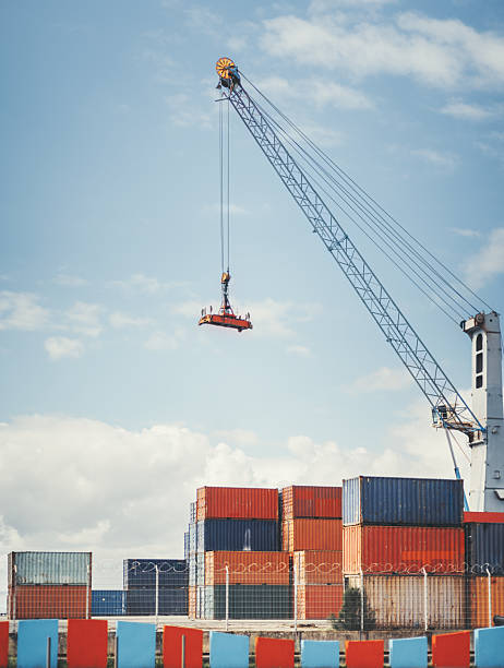 Airplane flying above container port.