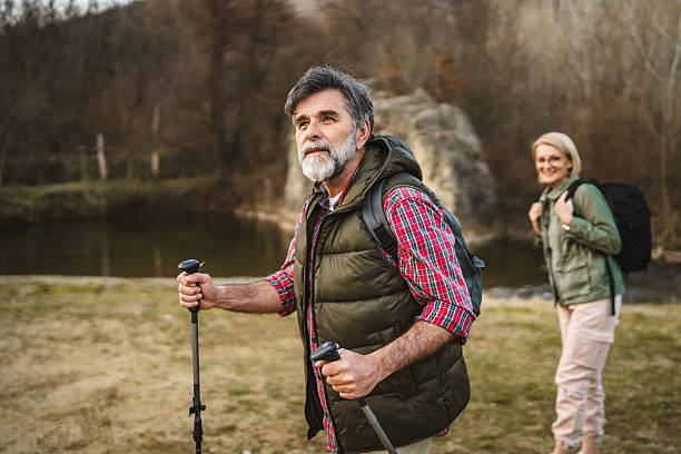 istock mature man hiker backpacker explore forest and river with hiking sticks 2205140960