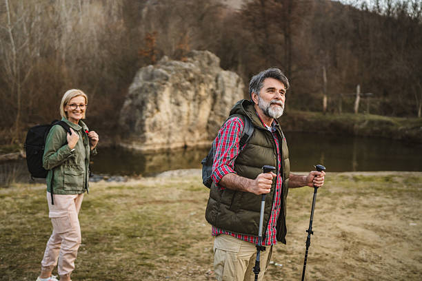 istock mature man hiker backpacker explore forest and river with hiking sticks 2205141090