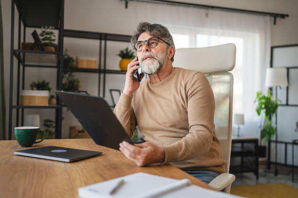 istock mature man talk on mobile phone with client and work at home office 2205143021
