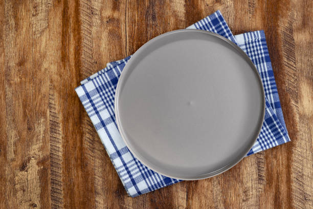istock Minimalist gray plate on rustic wooden table with blue checkered napkin. 2205143374