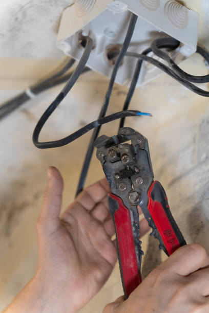 istock Electrician is working on electrical wiring, using wire strippers to carefully prepare wires for connection to a junction box during a home renovation or construction project. Vertical photo 2205158375