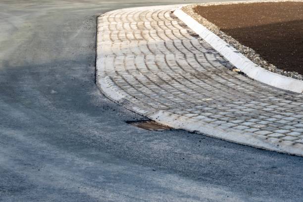 istock Cobblestone driveway entering asphalt road with drainage grate 2205158431