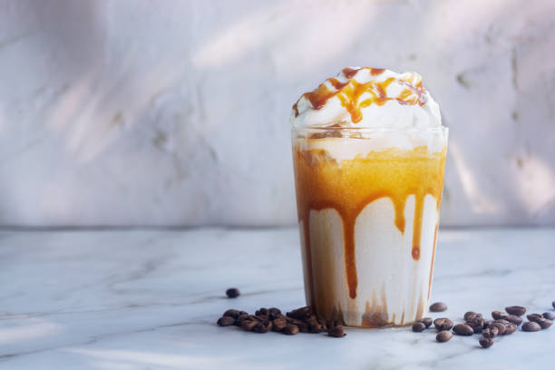 istock Iced caramel macchiato with whipped cream and caramel drizzle on top on white table. 2205171127