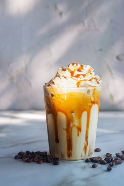 istock Iced caramel macchiato with whipped cream and caramel drizzle on top on white table. 2205171128