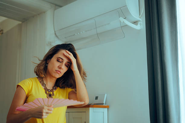 istock Woman Using a Hand Fan Having a Broken Air Conditioning Machine 2205174030