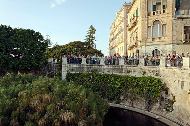 SYRACUSA, ITALY  SEPTEMBER 29, 2012: Tourists look around the fountain of Arethusa, she was the Naiad nymph of the sacred spring which bore her name in the Greek colony of Syrakousa (Syracuse) on the island of Ortygia on September 29, 2012 in Syracuse, Italy
