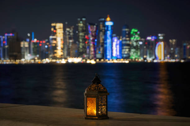 Doha, Qatar - March 14, 2025: Lantern with dusk sky and Doha Skyline bokeh light background for the Muslim feast of the holy month of Ramadan Kareem