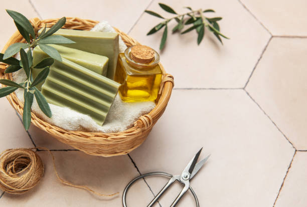 istock Olive soap bars, essential oil and scissors resting in wicker basket on tiled surface 2205186138