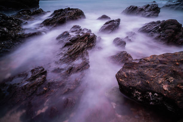Beach rocks or stone with soft waves at sunset as a background.