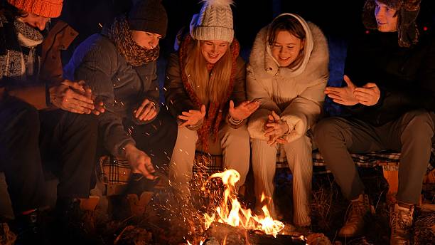 istock Friends sitting around a campfire in the woods on a winter evening 2205190610