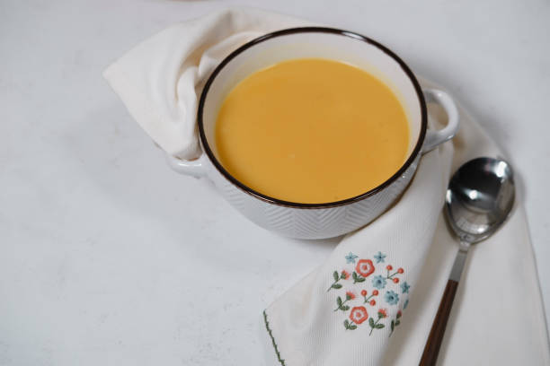 istock vegetable, vegan soup with cauliflower, carrot, pumpkin on white background with kitchen  textile table napkin and spoon 2205191974
