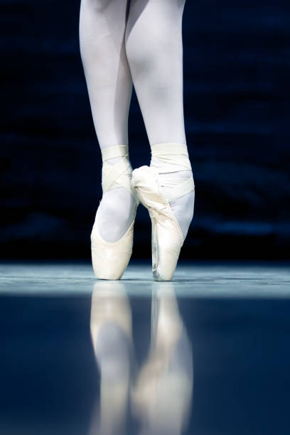 Close-up of a ballet dancers legs in pointe shoes, highlighting balance, strength, and elegance in a poised dance position.