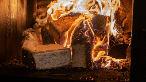 istock Eco-friendly compressed wood briquettes ignite a warm, inviting fire in a modern stove, showcasing sustainable heating and cozy ambiance for any home 2205205629