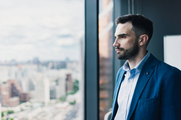 istock Business Professional Looking Thoughtful by a Window in the Office 2205209185