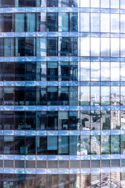 istock Modern glass building reflecting urban cityscape on its surface 2205209654