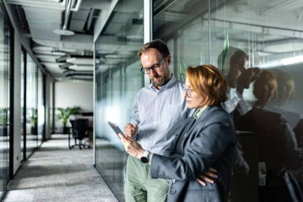 istock Two professionals discussing work tasks in a modern glass office environment 2205209836