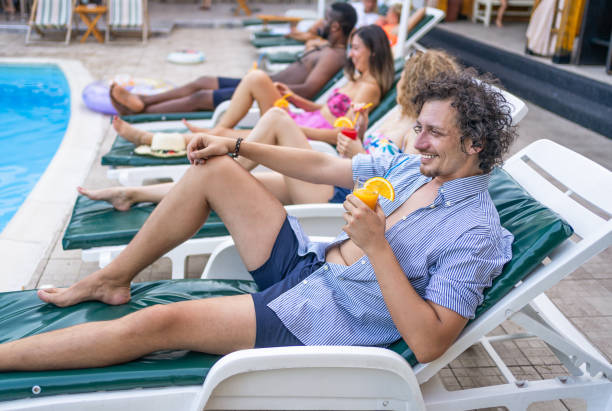 istock Young man enjoying on a sunbed by the swimming pool 2205210509