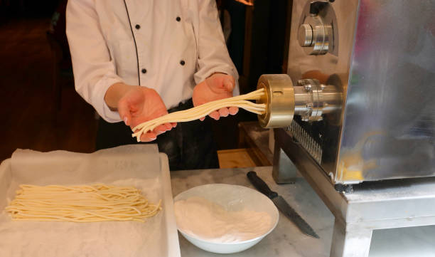 istock female pasta maker during the process of extruding fresh egg pasta and the machine that produces thick spaghetti 2205211838