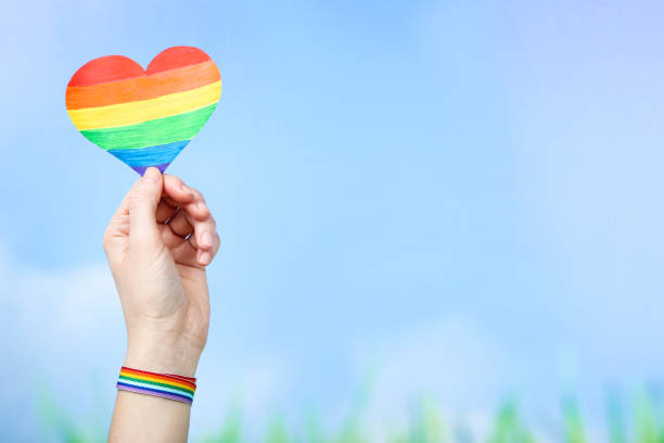 istock Female hand holding rainbow paper heart on blue background 2205215535