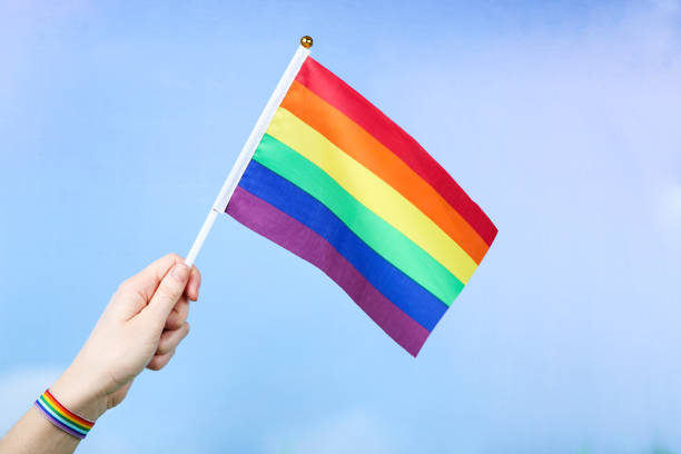 istock Female hand holding rainbow flag on blue background 2205215569