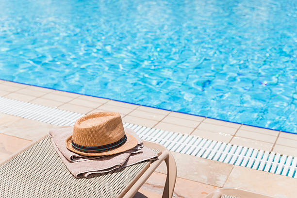 istock Sun hat and towel on a swimming pool deck chair 2205217694