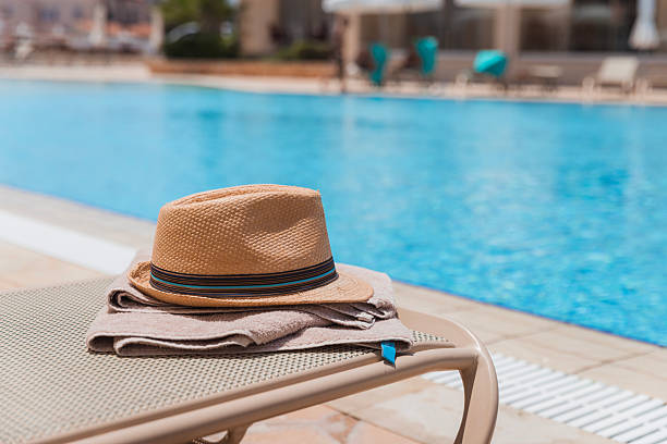 Sun hat and towel on a swimming pool deck chair