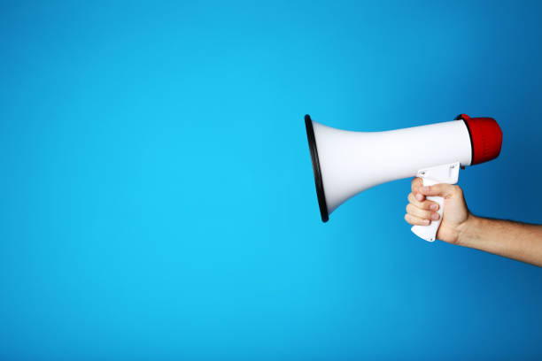 istock Female hand holding megaphone on blue background 2205220427