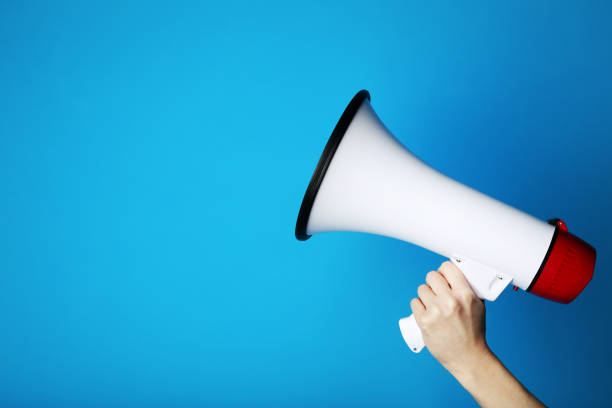istock Female hand holding megaphone on blue background 2205220452