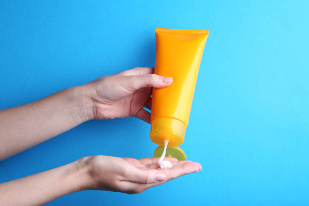 istock Female hand holding sunscreen cream on blue background 2205220734