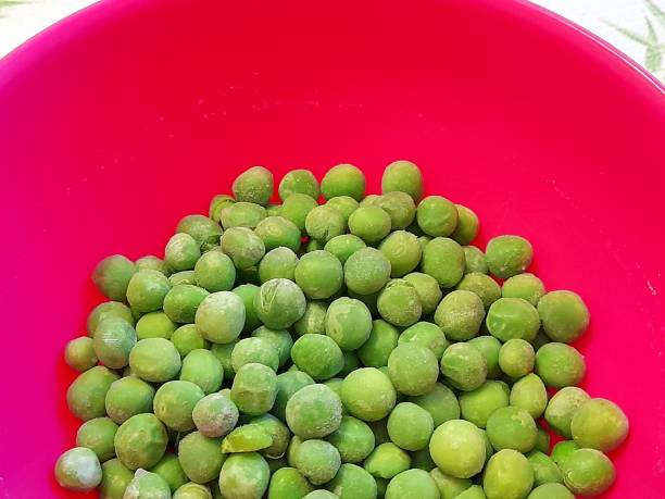 istock Frozen green peas in pink bowl 2205221257