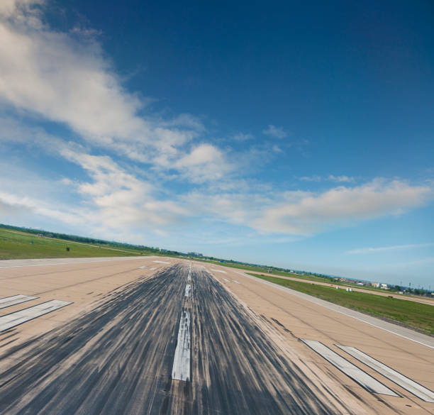 Low angle view of slanted airport runway, lofty clouds above