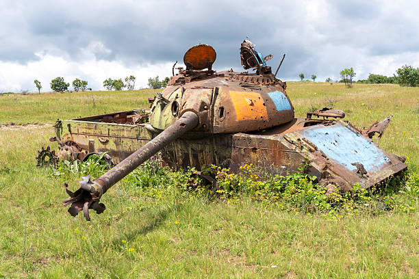 istock Old destroyed T-54 Russian tank on a grassy field 2205237203