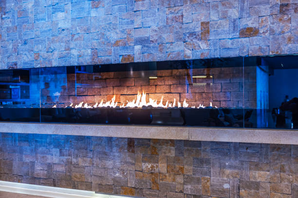 Modern gas fireplace with glass panel and stone wall in luxury hotel lobby, creating warm and elegant ambiance. Mexico.