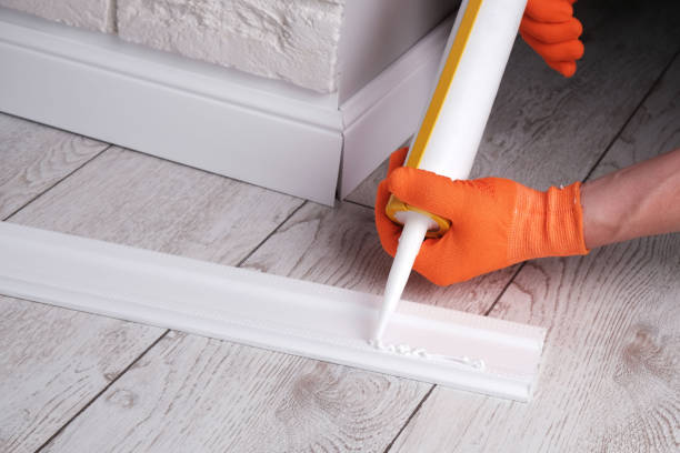 istock master applies glue to  skirting board with  glue gun 2205242382