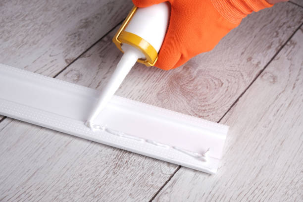 istock master applies glue to  skirting board with  glue gun 2205242388