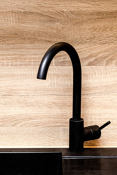 istock Modern Black Kitchen Faucet and Sink Against a Wooden Backsplash 2205245924